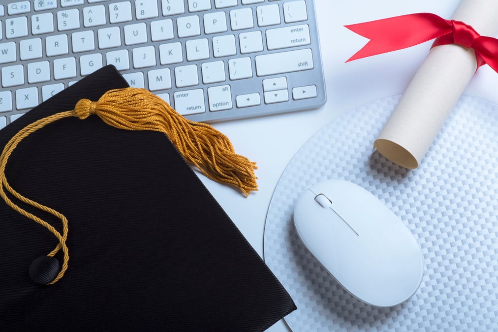 graduation cap, diploma, keyboard and mouse next to each other on a table
