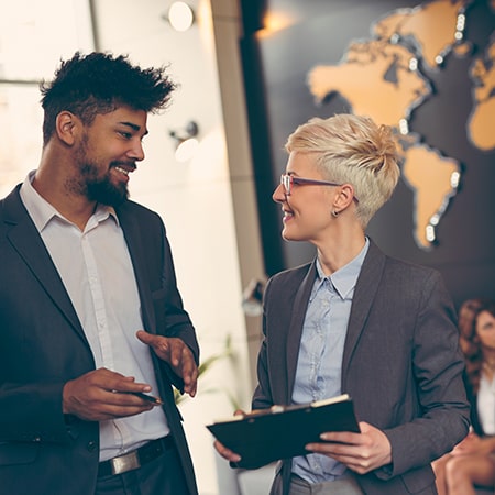 Two coworkers discussing international solutions with world map in background