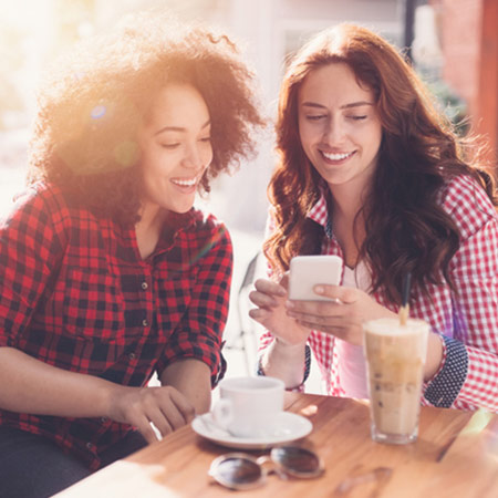Two friends lean together to look at a phone.