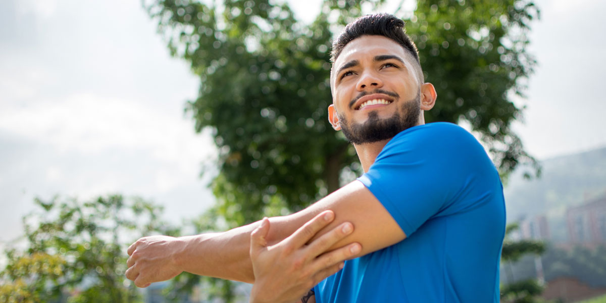 college student outside stretching their arms and preparing to exercise