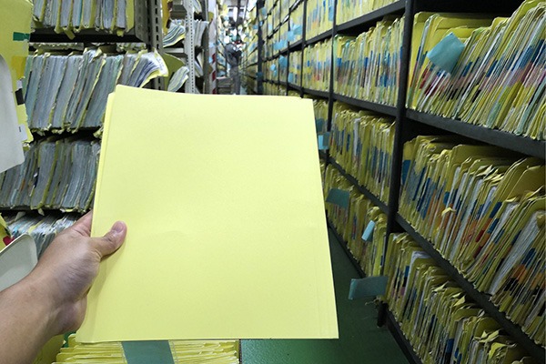 Close up of hand holding file folder in records room