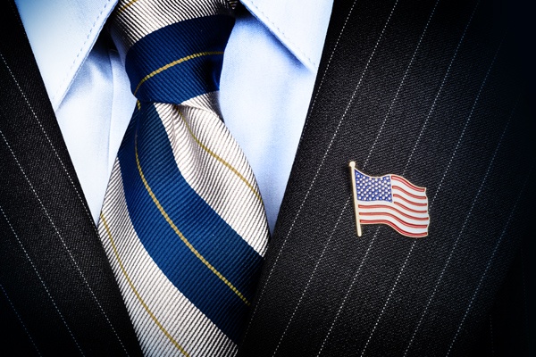 Close up of an American Flag pin on the label of a pinstripe suit.