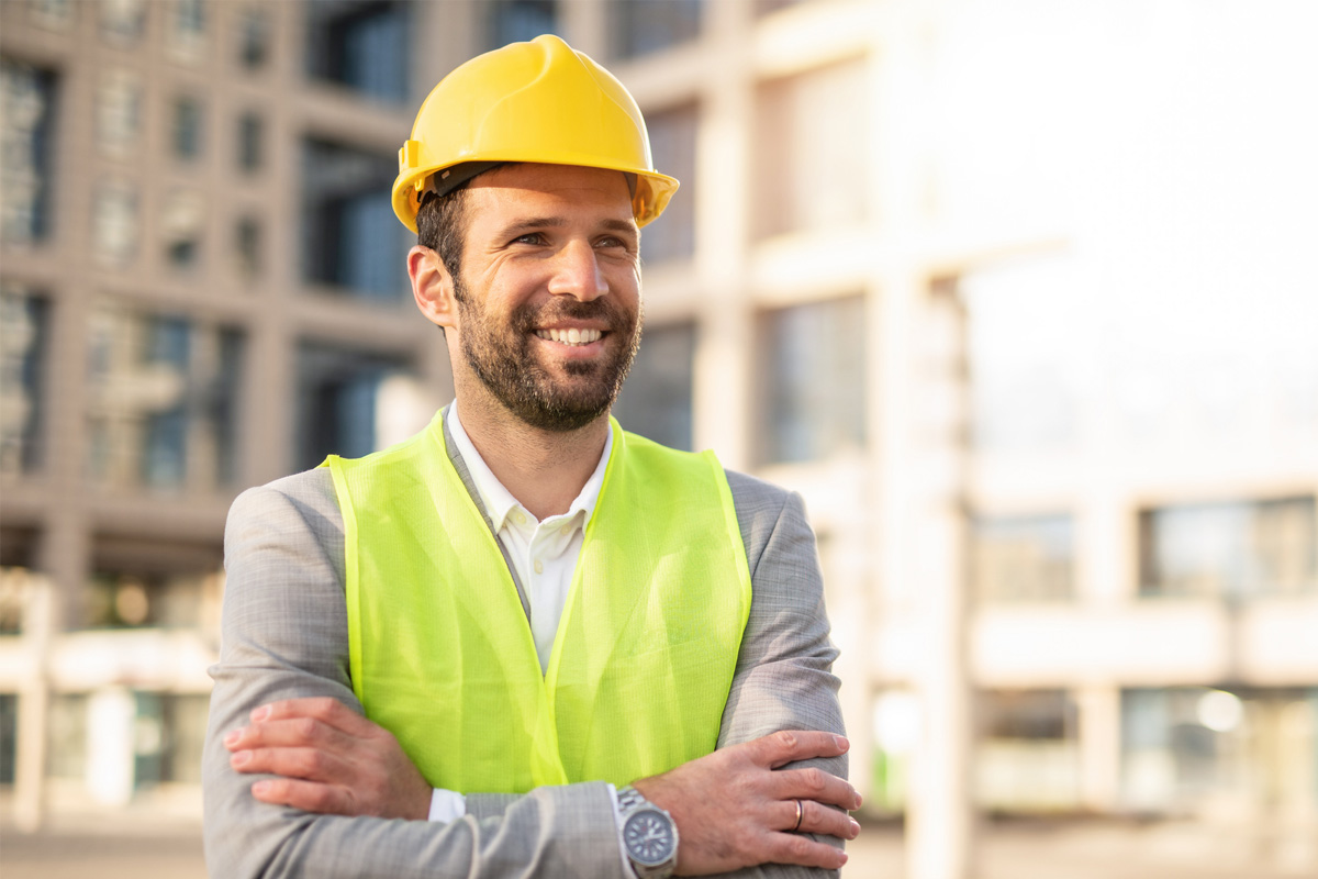 safety professional standing in front of building crossing arms and smiling