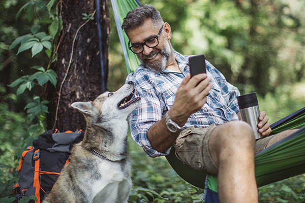 Man sitting in hammock smiles at his dog