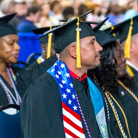 Group of graduates with focus on male wearing American flag stole