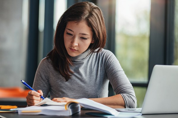 Student takes notes from a textbook