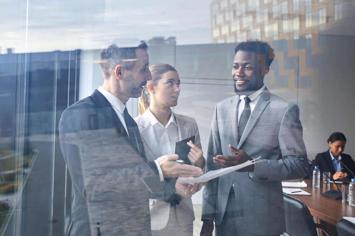 Government professionals standing near a conference room table and talking