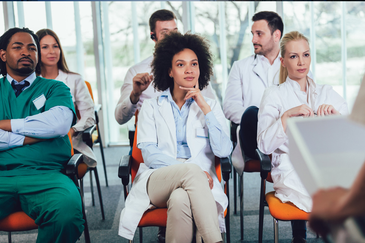 Health care professionals sitting in rows and listening to a speaker