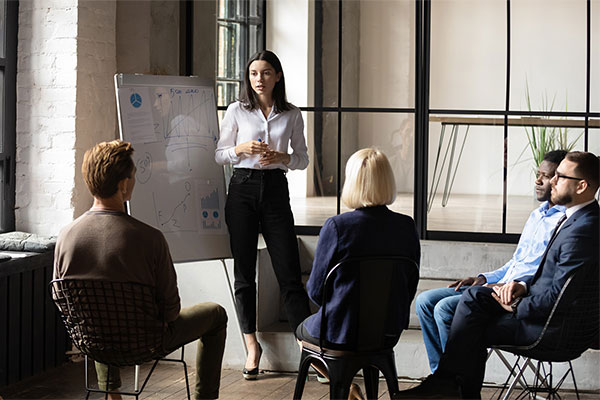 leader standing and other team members sitting by white board and discussing public administration