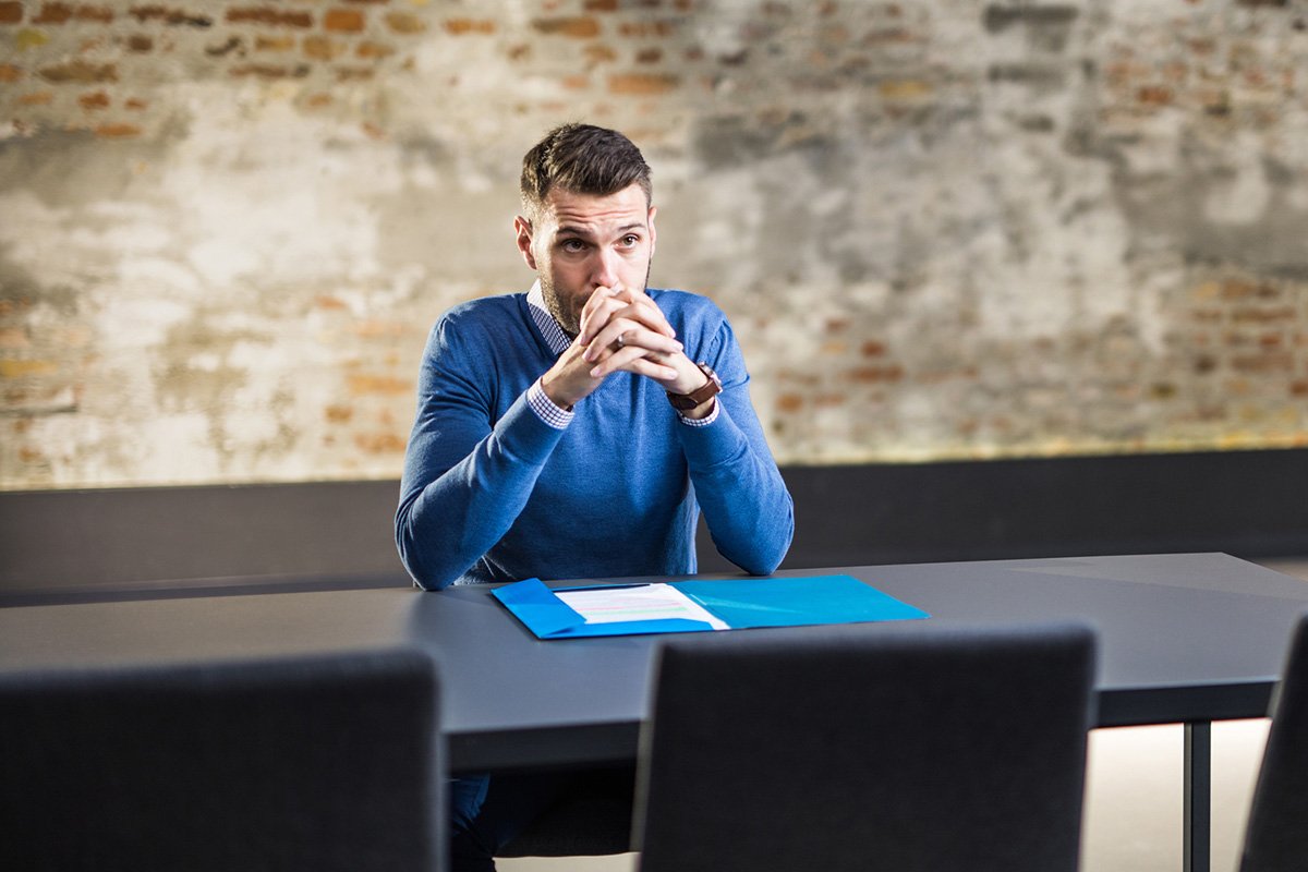 A man in business dress nervously awaits his interviewer.