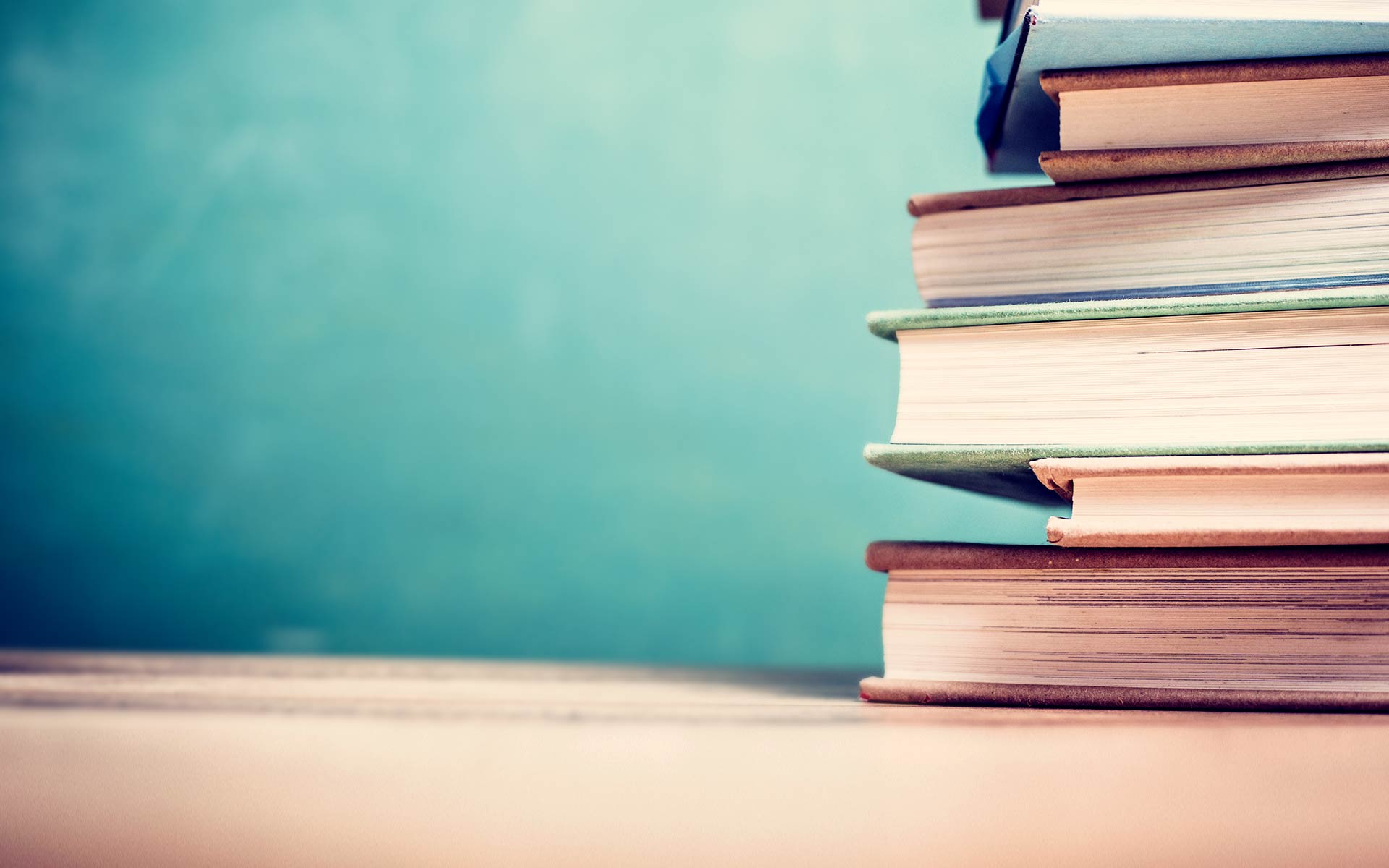 A tall stack of books sits on a table