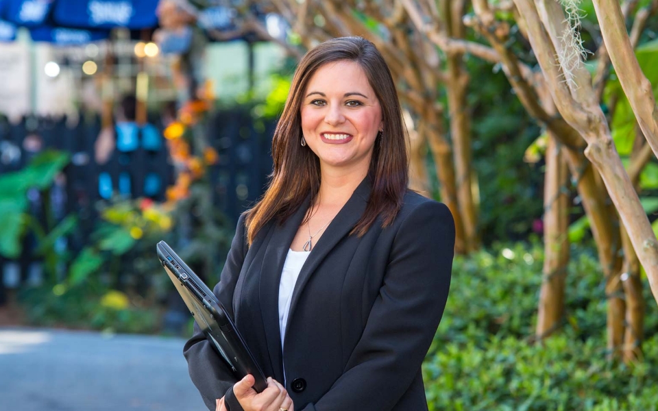 White woman in a business suit holding her laptop