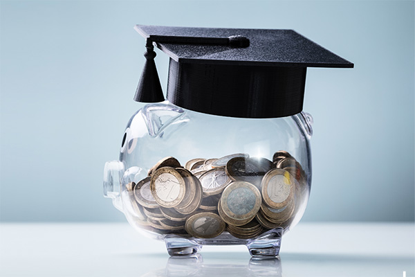 Clear piggy bank with coins inside wearing a graduation cap