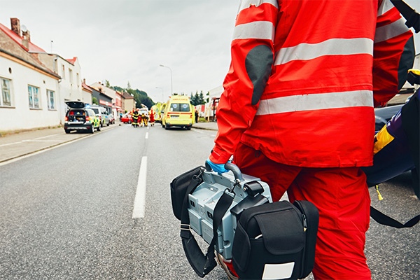 ems professional carrying supplies and walking down a street toward emergency vehicles and first responders