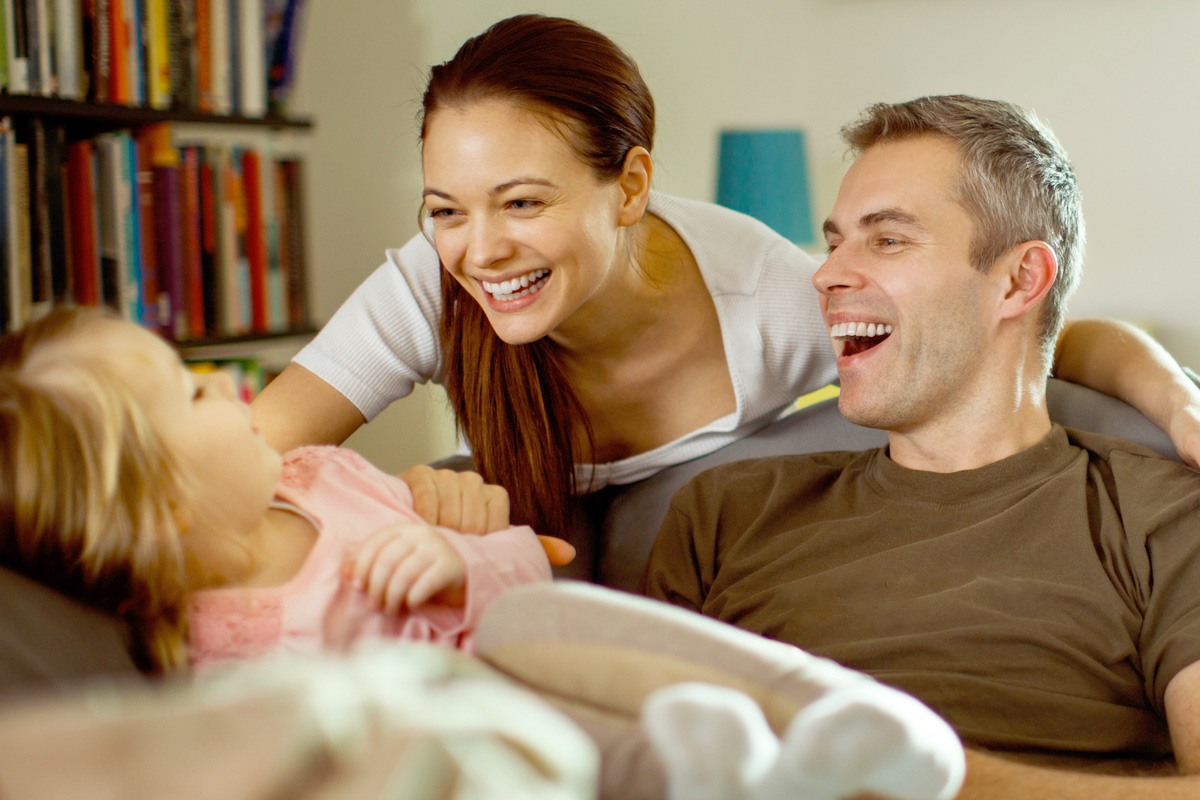Military service member and their spouse laughing and playing with their child