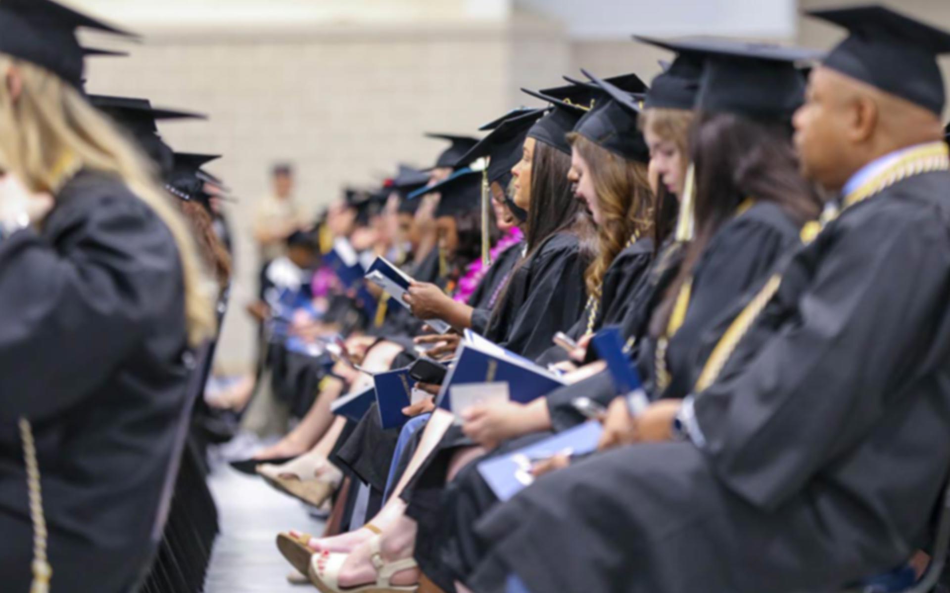 Graduates in an auditorium waiting to hear their name