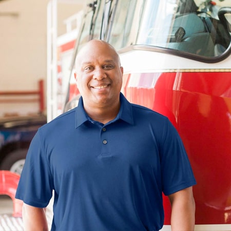 Daryl Hogan in navy blue polo standing in front of an emergency vehicle