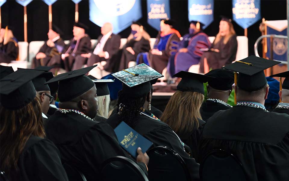 CSU graduates sit facing the faculty on stage during commencement