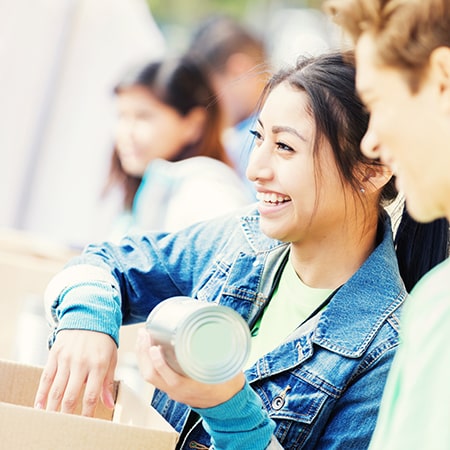 woman handing out canned food