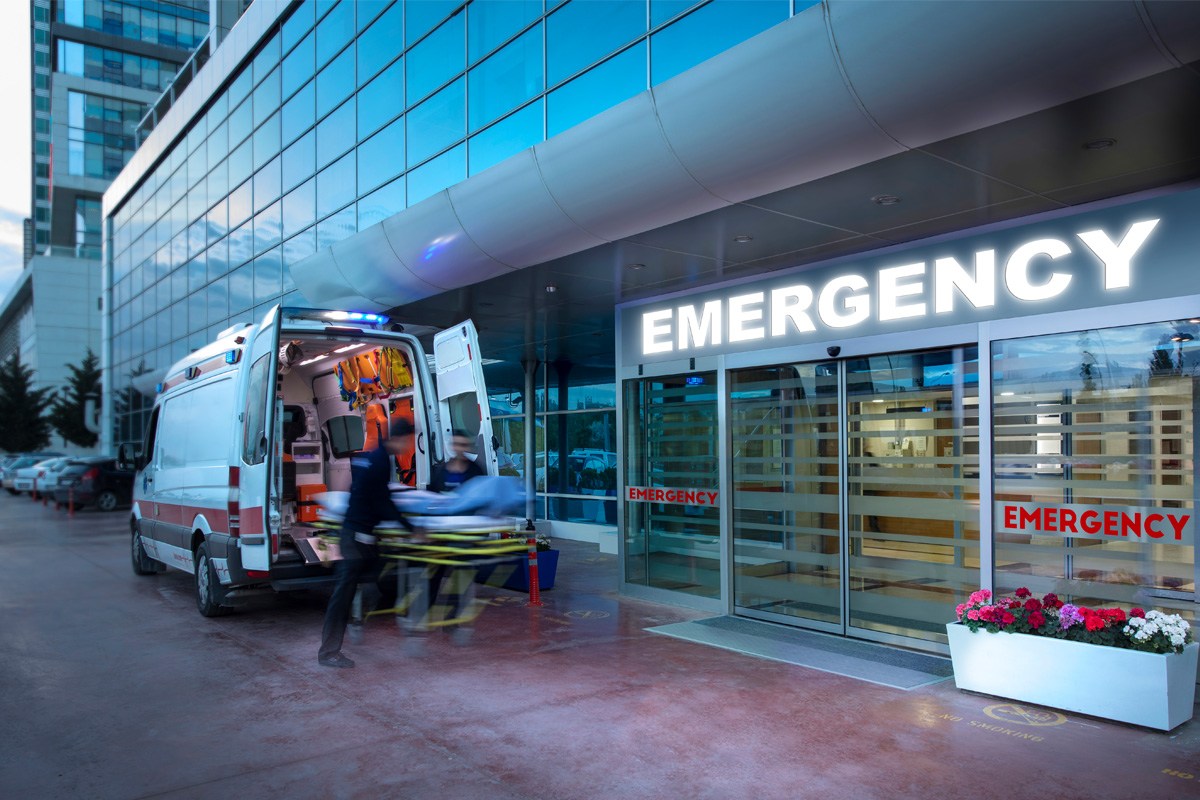 A blurred scene of two EMTs unloading a gurney from an ambulance at an emergency room entrance