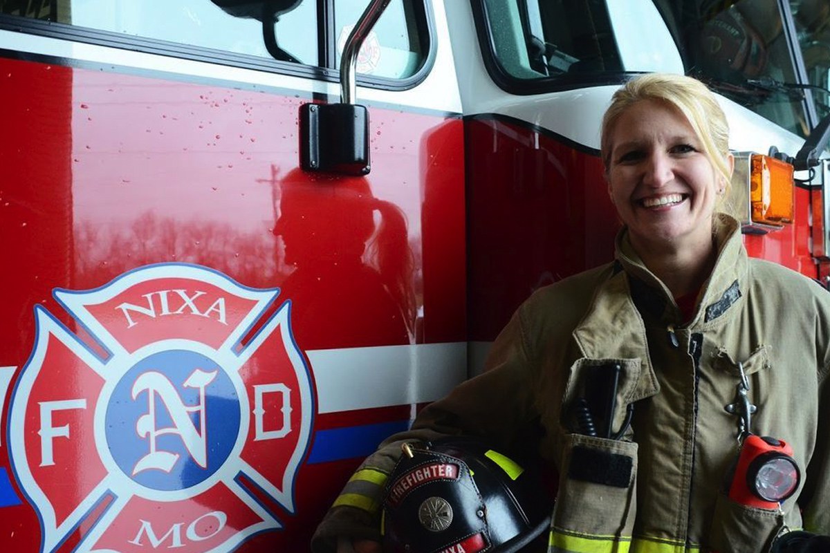 Donna Osborne smiles in front of a fire truck.