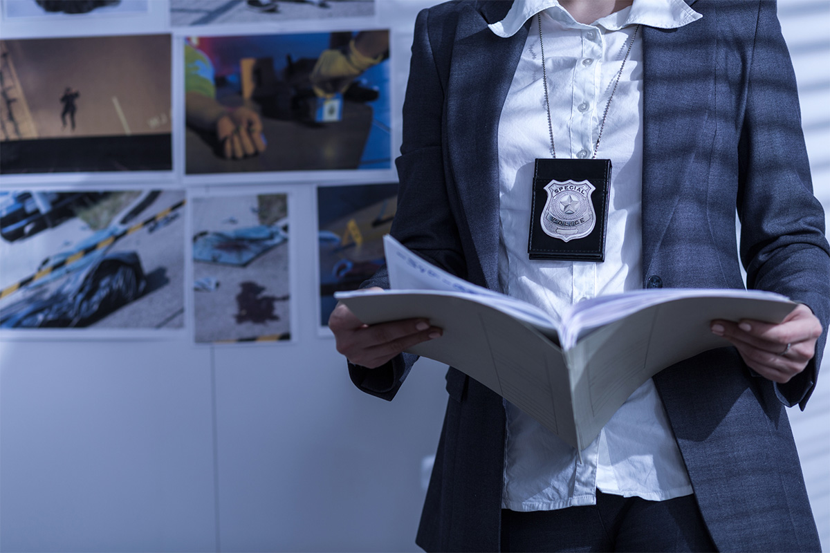 law enforcement officer pictured standing from the neck down and looking at documents