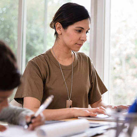 Veteran mother works on computer while kids do homework