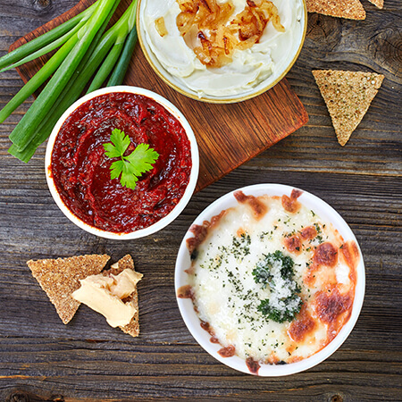 Looking down on a table display of veggies, appetizer dips and crackers