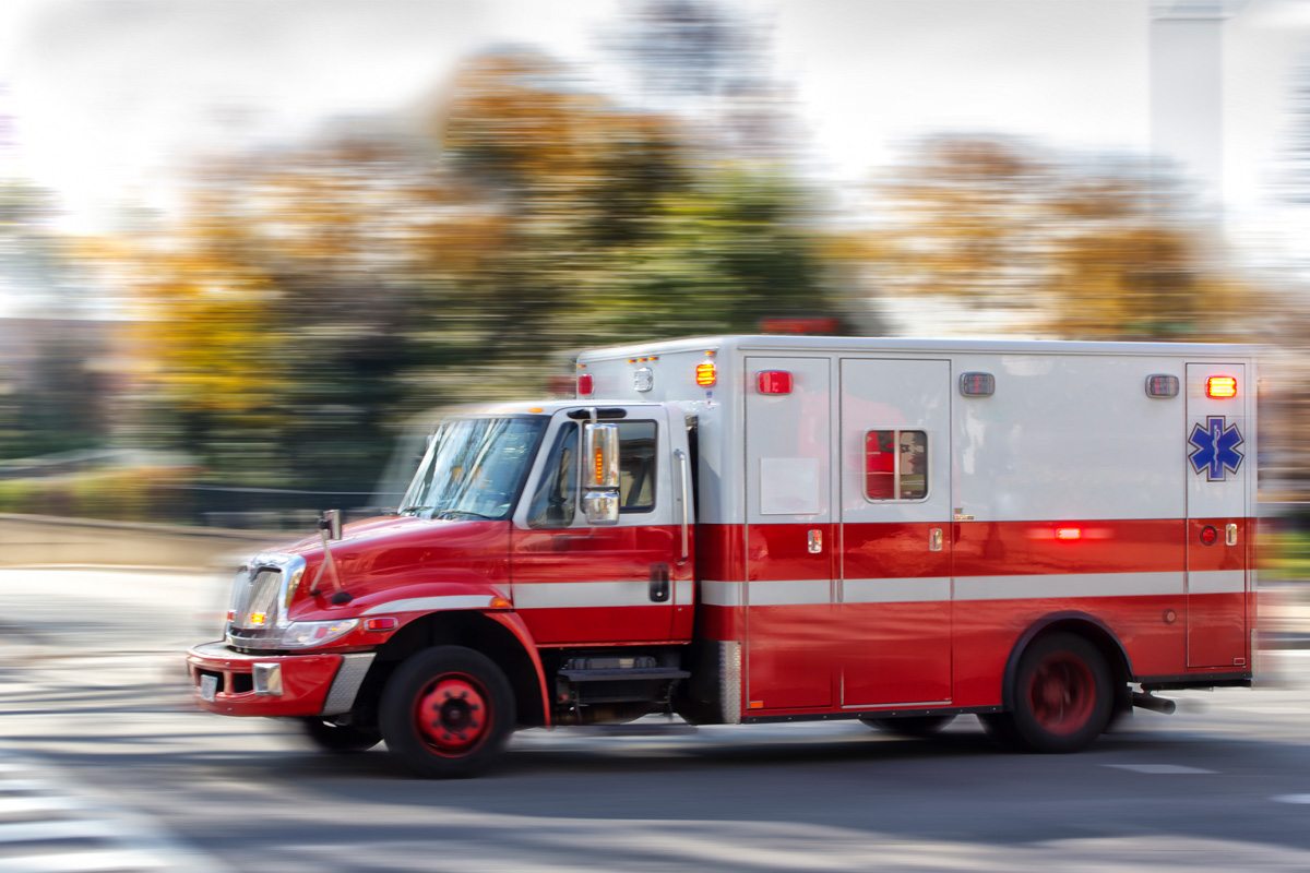 An ambulance blurred by speed as it races down the street.