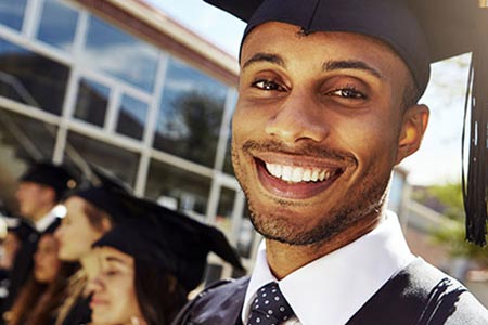 Young graduate smiles with fellow graduates in the background