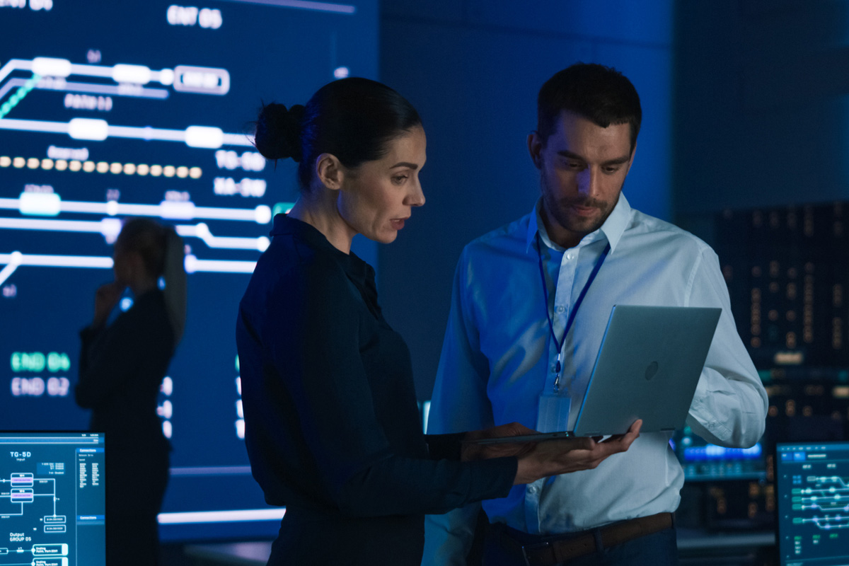 Two cybersecurity professionals standing and looking at a laptop computer screen