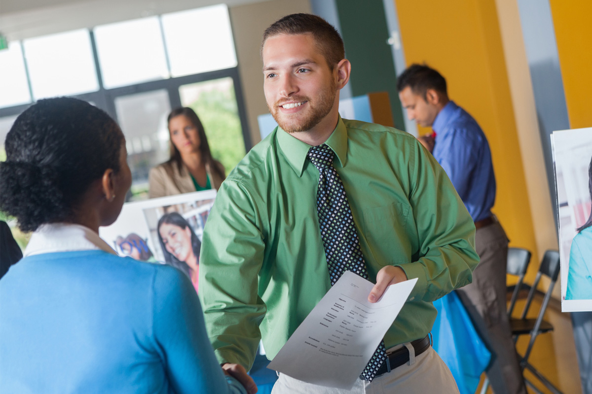 veteran holding a resume and shaking hands with a civilian job recruiter