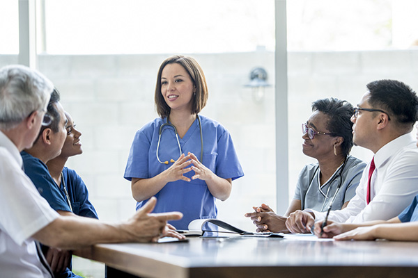 public health professional wearing scrubs while standing and talking to a group of colleagues