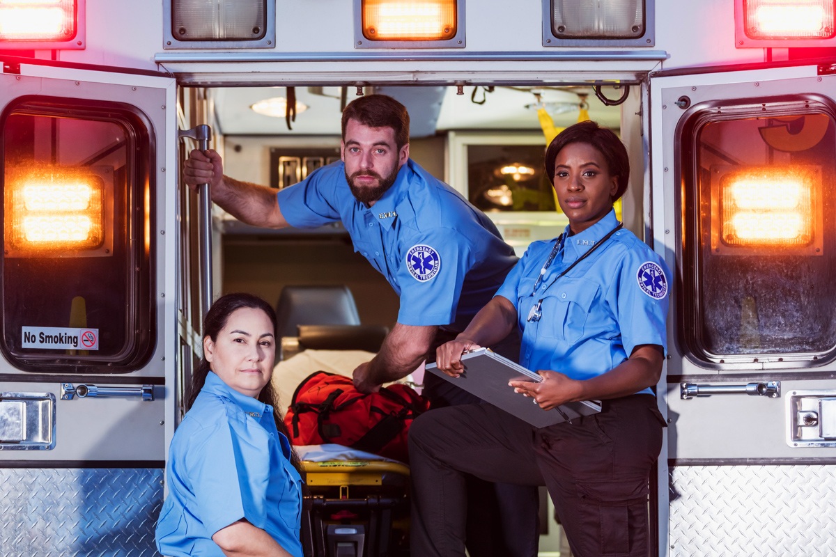 Three EMTs pose in an ambulance.