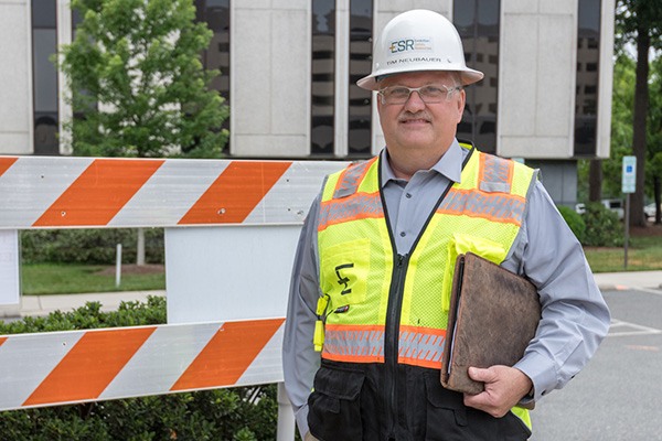 Tim Neubauer smiles in a safety vest and hard hat.