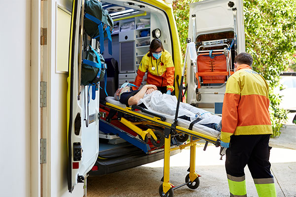 EMS professionals moving a patient on a gurney into an ambulance