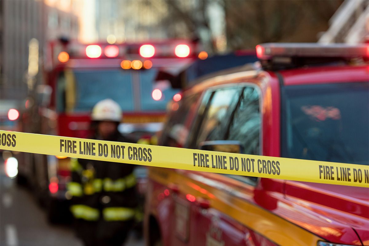 Caution tape "Fire line do not cross" in front of several fire department vehicles.