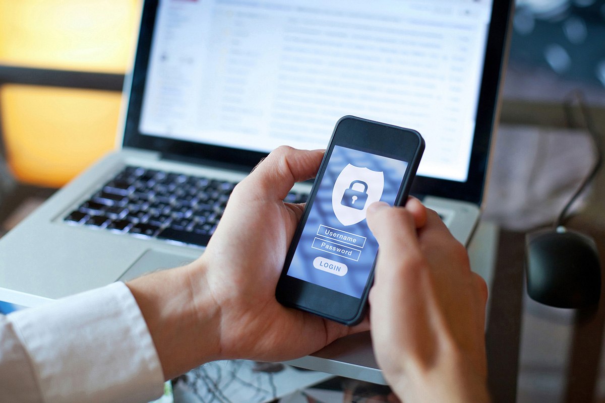 Hands holding a cell phone displaying a secure login screen.