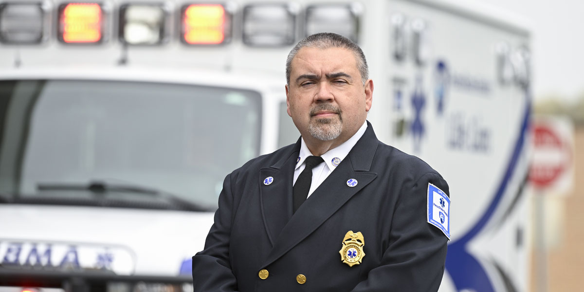 ems professional standing posing for picture in front of ambulance