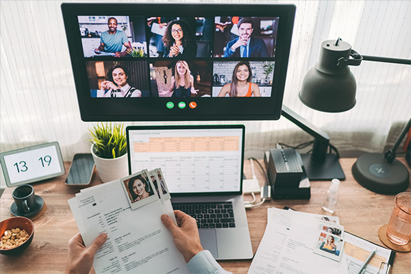 point of view industrial-organizational psychologist sitting at a desk during a video conference call and holding documents