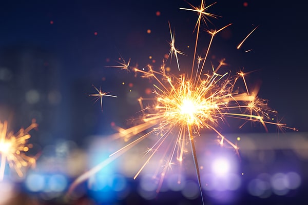 Glittering burning sparkler against blurred city light background