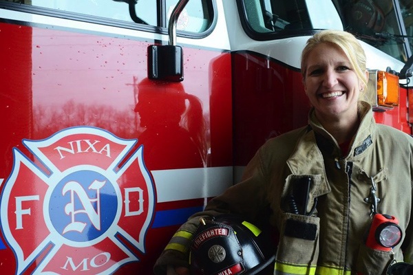 Donna Osborne smiles in front of a fire truck.