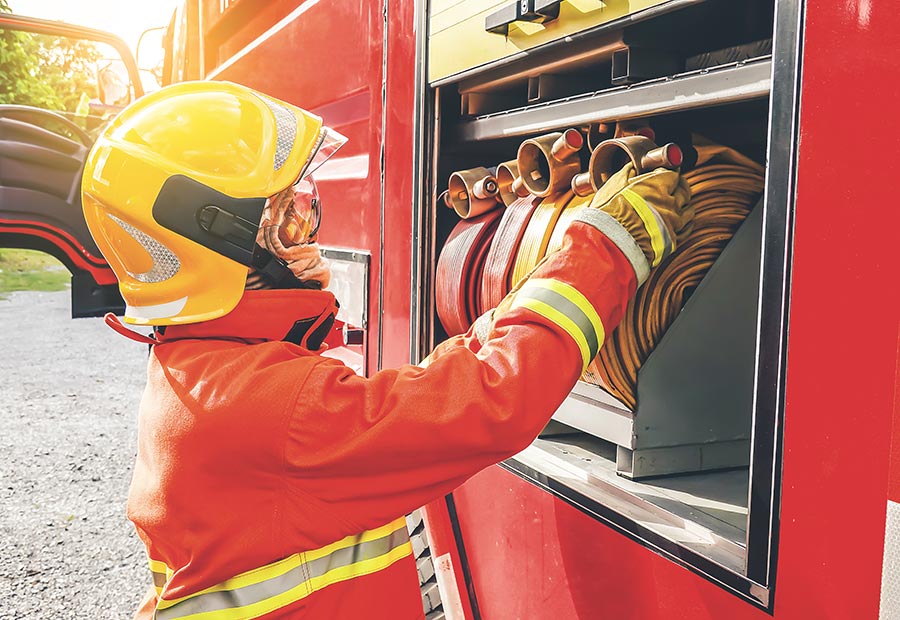 Firefighter unrolling hose off fire truck