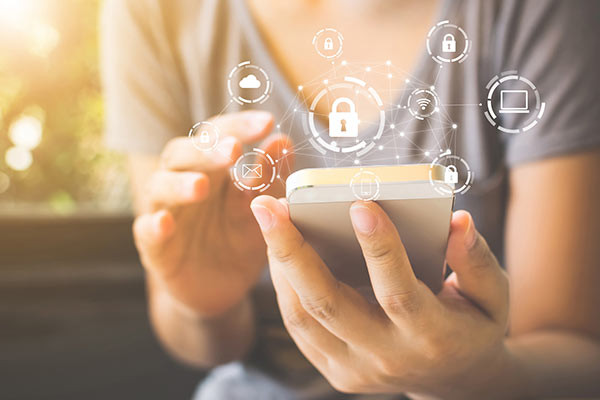 Close up of hands holding cell phone with overlaid icons representing cloud data and security