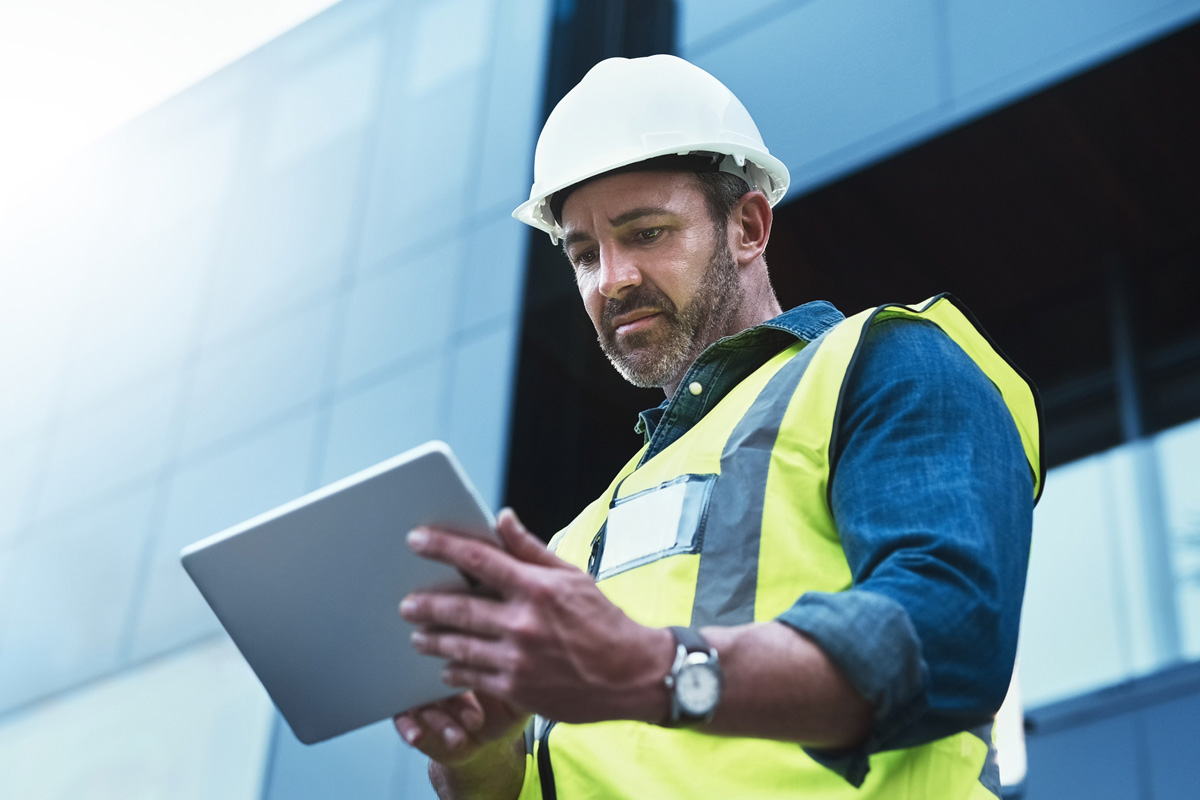 occupational safety and health professional standing in front of building and using a tablet