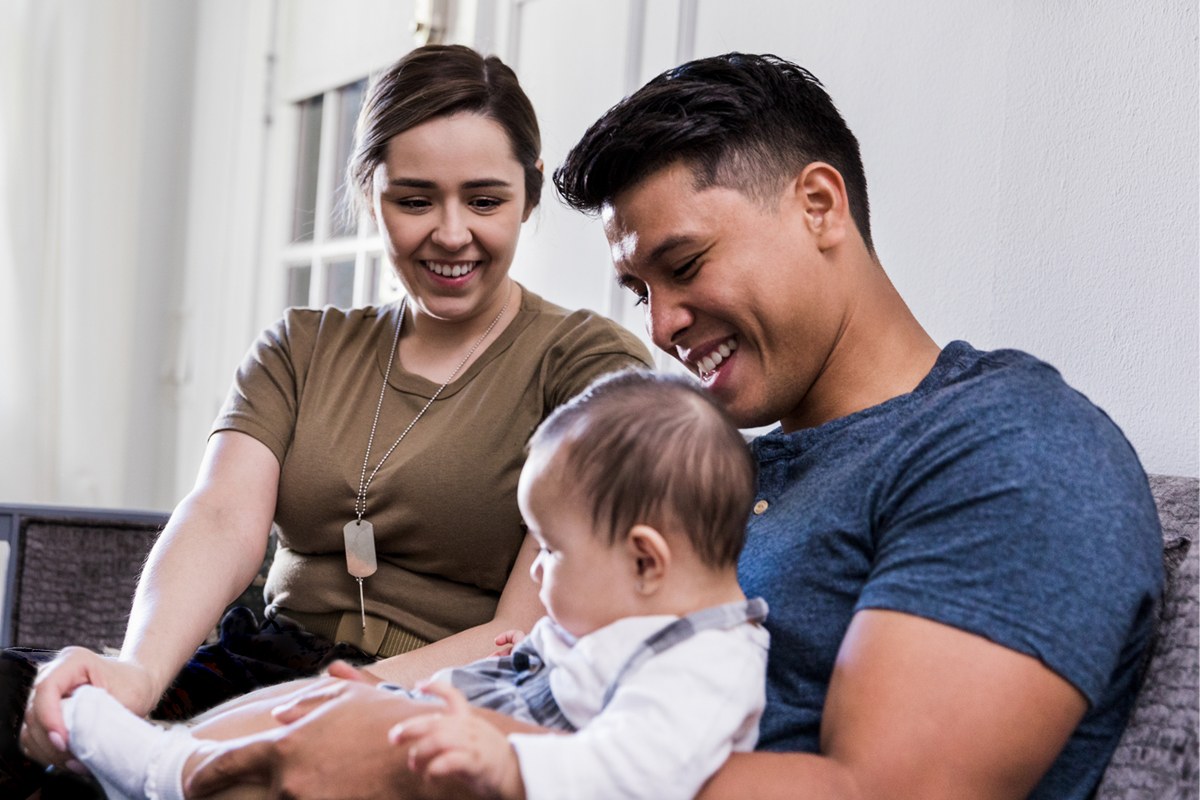 military service member sitting with their spouse and child