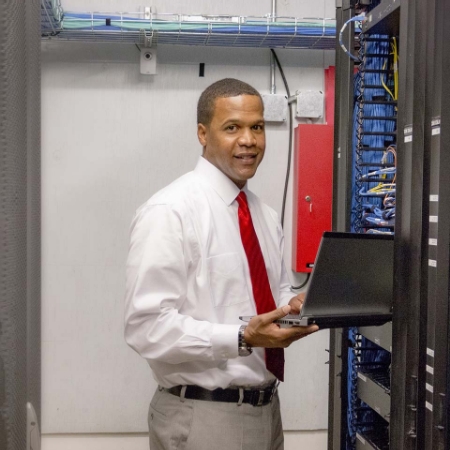 African American man works on a laptop in a server room
