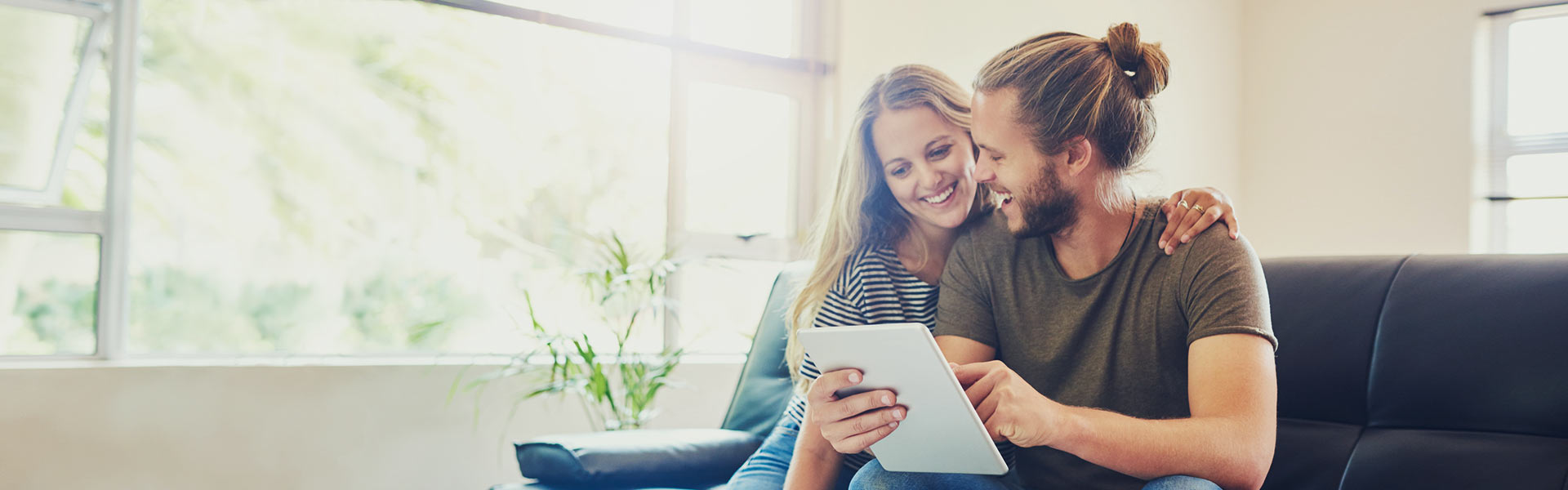 smiling couple look at a tablet together