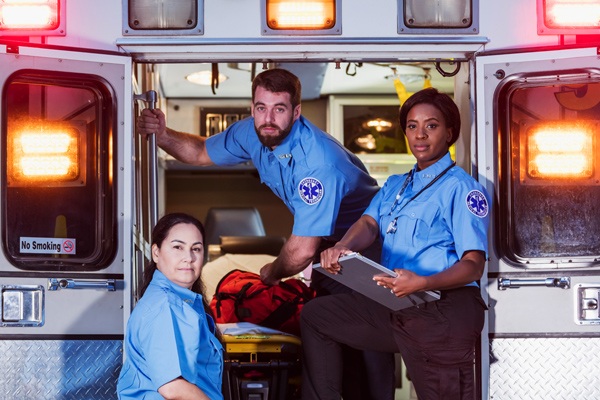 Three EMTs pose in an ambulance.
