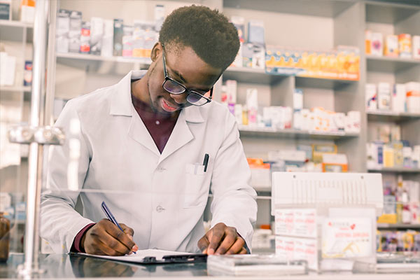 Pharmacy technician writing on clipboard